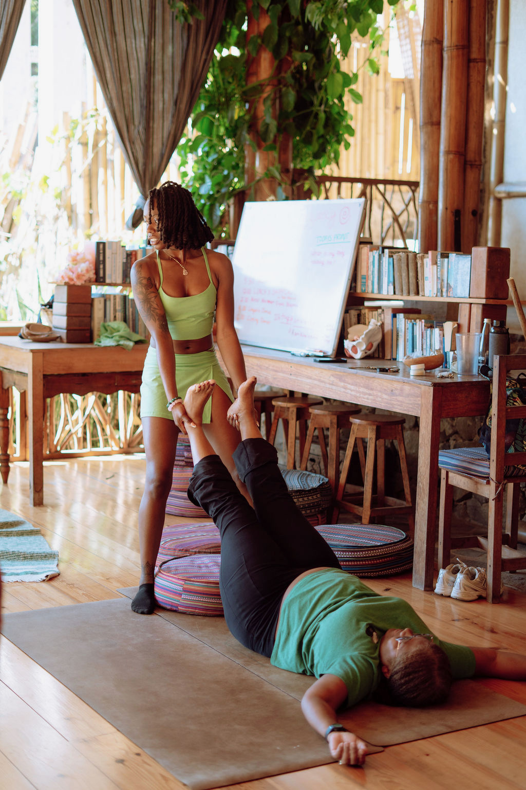 Empress supporting a participant's lifted legs for an assisted hamstring and calf stretch